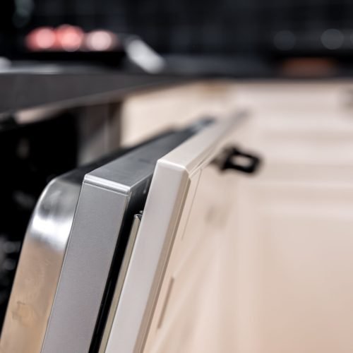 Macro detail of a stainless panel edge under a dark countertop with soft bokeh background. Modern appliance mood with premium clean aesthetic for smart home themes.